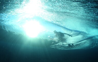 surfer riding a wave from an underwater view