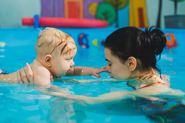 Swimming pool for training newborn children to swim. Baby swimming in the pool. Teaching a newborn boy to swim in a pool with a coach