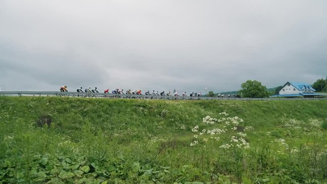 A group of cyclists ride on the horizon on the road, compete with each other in bicycle races. Bicycle race among professional athletes. Mountain area