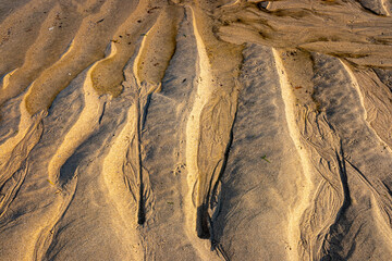water rills on the shore of a beach during low tide at sunset