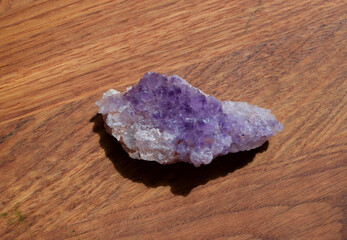 Beautiful lilac druse with amethyst crystals on a wooden background. Magical semi-precious stones.