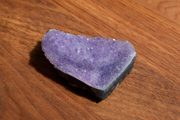 Beautiful lilac druse with amethyst crystals on a wooden background. Magical semi-precious stones.