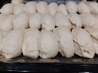 Several sweet filled pies ready for baking, lying on a baking sheet, top view. 
