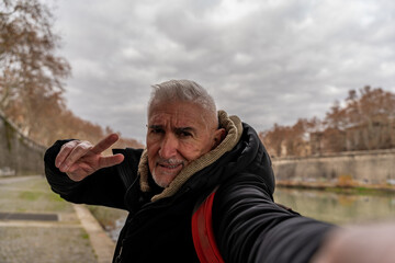 happy middle aged man on vacation taking a selfie on the banks of the Tiber river in rome