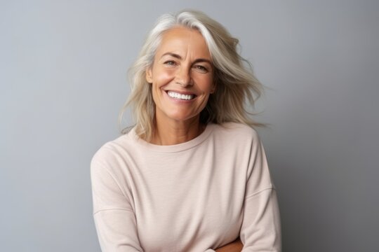 Portrait of happy mature woman with blond hair over grey background.