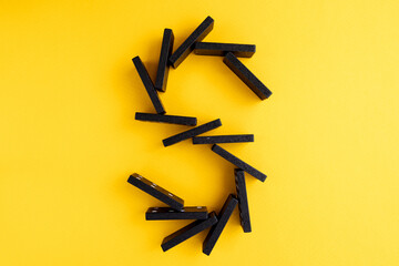Black domino on a yellow background. Domino effect concept. Business, risk, management and finance...