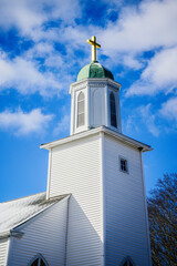 Chapel with golden cross and the blue sky with white clouds, close-up