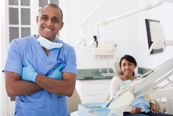 Professional dentist standing in office with patient background