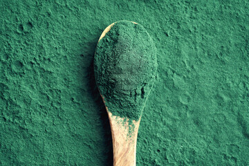 Green spirulina powder on a spoon - nutritional supplement
