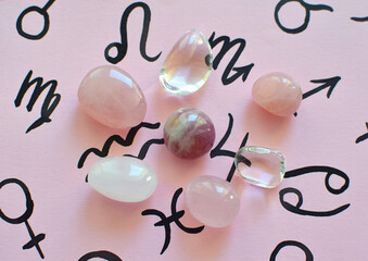 Beautiful crystals and rose quartz on a pink background with symbols of the zodiac signs. Magic...