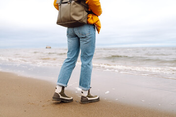 Close-up of woman's legs in boots. Tourist walk along beach near the sea. Adventure, vacation...