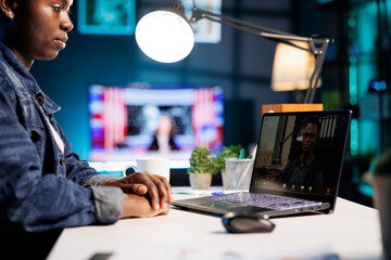 Close-up of african american freelancer sitting at table at home having video conference with male...