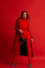 Fashionable confident woman wearing trendy red midi coat, turtleneck sweater, leather pants, zebra...