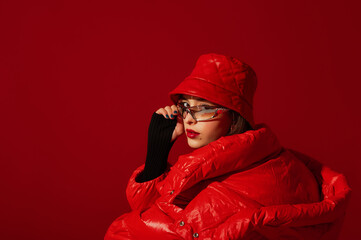 Fashionable confident woman wearing trendy y2k style silver glasses, quilted faux leather bucket...