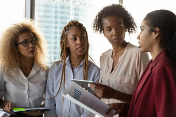 Giving explanation. Millennial black women employees listen to team leader expert advice on...