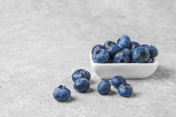 Fresh blueberries in a small square bowl on gray concrete background with copy space. Organic berries, healthy food, wild berries