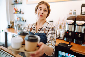 Portrait of beautiful young barista woman serving coffee with a big smile. Small business owner, food and drink industry concept.