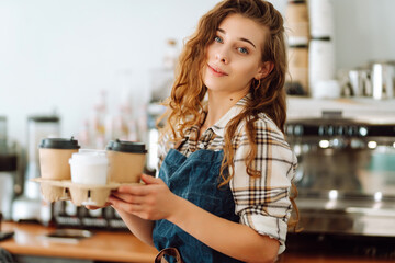 Portrait of beautiful young barista woman serving coffee with a big smile. Small business owner,...