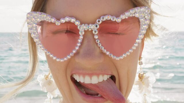 Close up portrait of fancy woman in glamorous pink glasses in the shape of heart. Super positive blonde lady with open smile and white teeth fooling around. Happy wedding day, St Valentines surprise