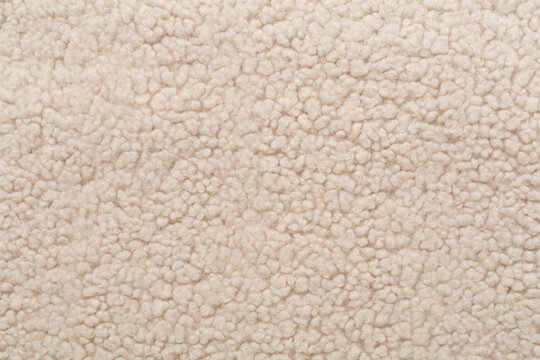 Beige cuddle teddy bear fabric as background, top view