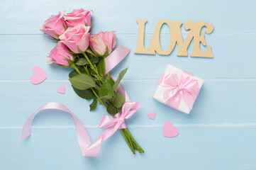 Pink roses with hearts and gift box on wooden background, top view. Valentines day concept