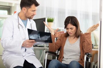Fototapeta premium emotional woman in wheelchair receives diagnosis from doctor