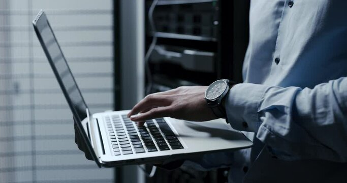 Technician hands, data center and laptop for maintenance, system and hardware or software backup in cybersecurity. Person typing on computer for engineering, coding and programming in a server room
