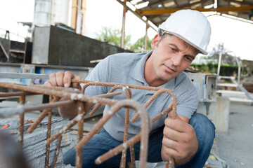man in overalls works with metal structure outdoors