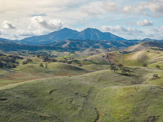 Aerial photography of rolling green hills and Mt.Diablo with a clouded blue sky