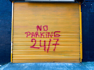 No parking 24/7 sign on a metal garage door - 712773439