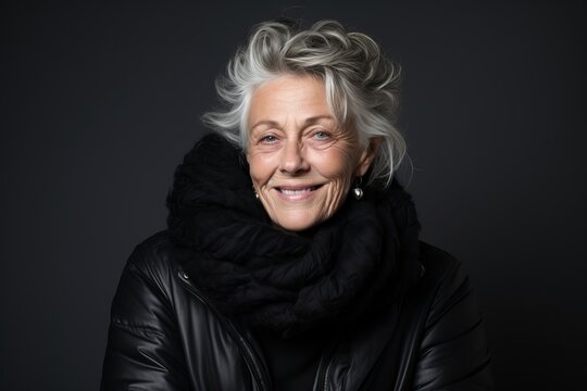 Portrait of a smiling senior woman in winter clothes on black background