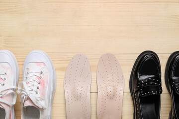 Stylish female shoes and orthopedic insoles on wooden background
