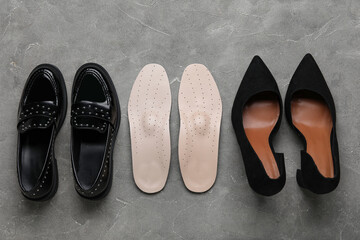 Pair of orthopedic insoles and stylish female shoes on grunge background