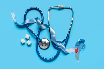 Awareness ribbon with stethoscope and sugar on blue background. Diabetes concept