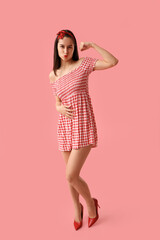 Portrait of strong pin-up woman showing muscles on pink background. Women's History Month