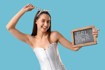 Portrait of young pin-up woman holding chalkboard with text GRL PWR on blue background. Women's History Month