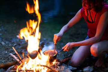 Mid Adult Woman Hiker Preparing a Warm Meal on a Campfire