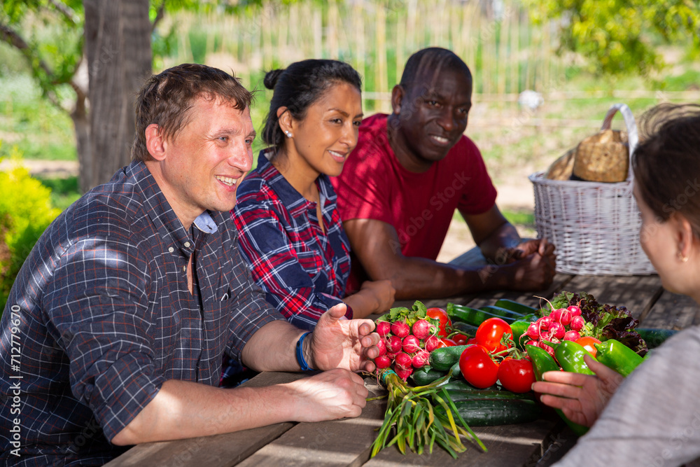 Wall mural happy farmers talking while sitting at table in the garden