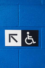 Handicap sign with an  arrow on a blue wall