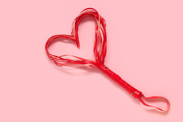 Whip from sex shop in shape of heart on pink background. Valentine's Day celebration