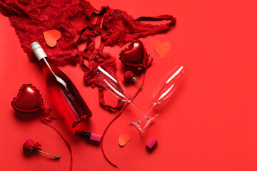 Composition with bottle of champagne, glasses, sexy lingerie and heart-shaped balloons on red...