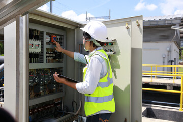 Young female engineer with green safety vest and white helmet work check and control electric...