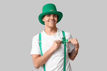Happy tattooed young man in leprechaun's hat and with shamrock on light background. St. Patrick's Day