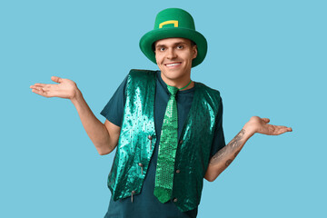 Happy tattooed young man in green clothes on blue background. St. Patrick's Day