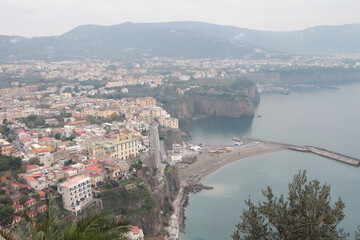amalfi coast mountain town village homes houses next to water ocean on foggy fog day shot from high...