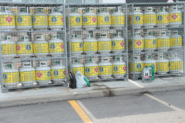 propane tanks on shelves in cages on curb in parking lot outside during summer