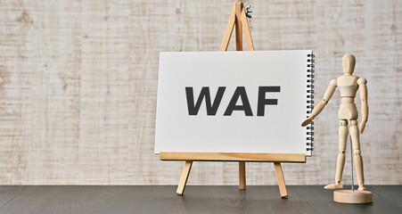 There is notebook with the word WAF. It is an abbreviation for Web Application Firewall as eye-catching image. - obrazy, fototapety, plakaty