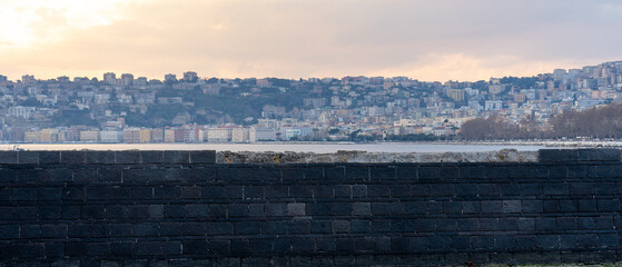 black wall with city in the background across the Tyrrhenian sea from the egg castle. Naples, Italy