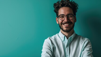 Smiling young man with glasses against a teal background