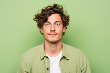 Fototapeta na wymiar Handsome young man with curly hair and green shirt on a green background